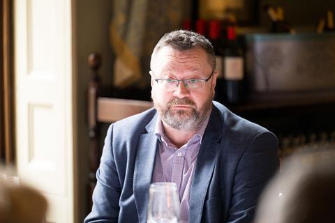 Photograph of ABI chief fraud and financial crime officer Mark Allen. He wears a blue and purple gingham shirt with a navy blazer over the top.